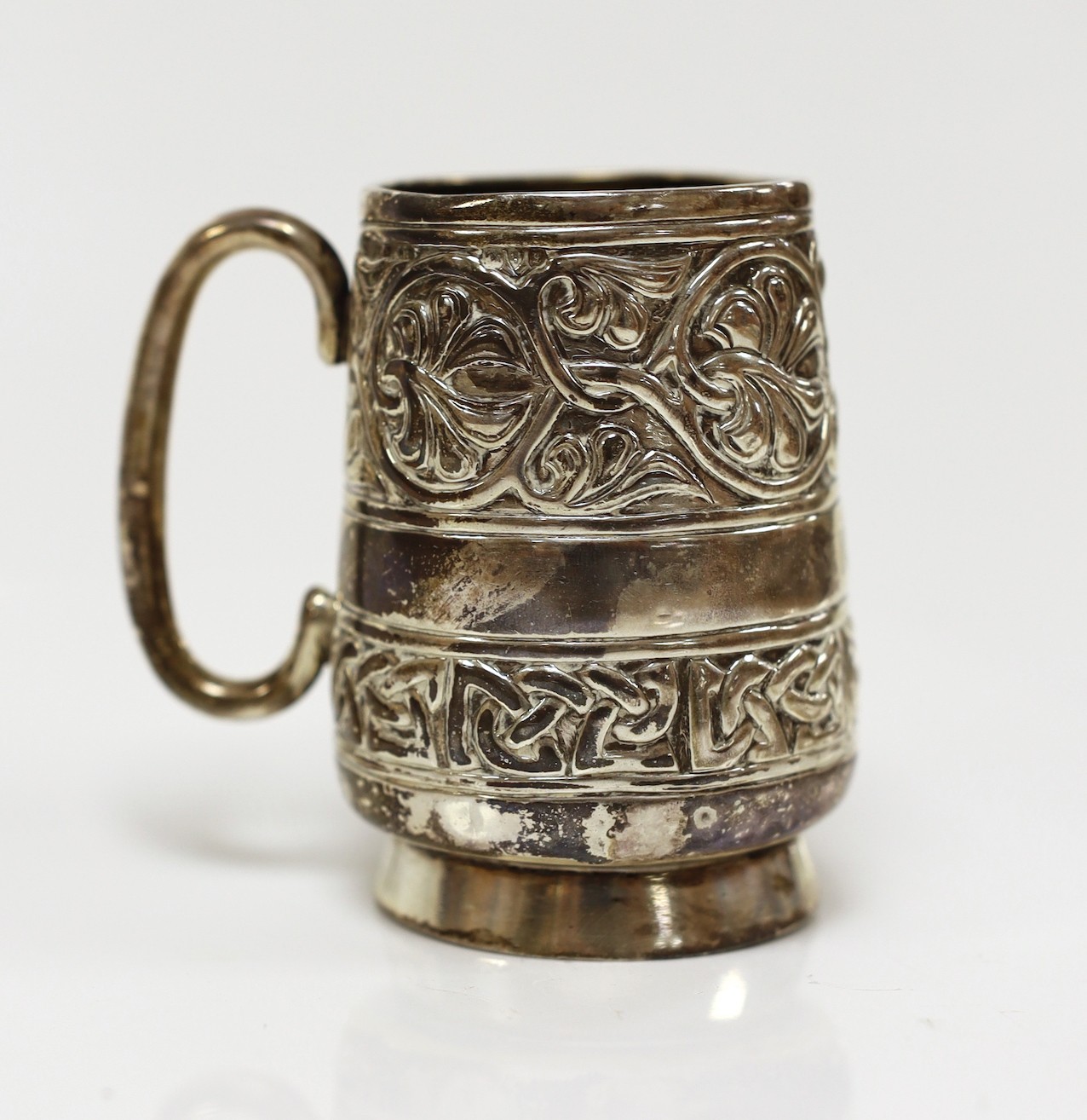 A George V embossed silver Iona mug, by Alexander Ritchie, Chester, 1911, with engraved initials, height 86mm, 1018 grams.